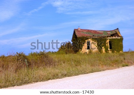 An abandoned house on the side of a country road.