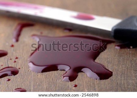 A red liquid puddle with knife. Could represent juice or blood.