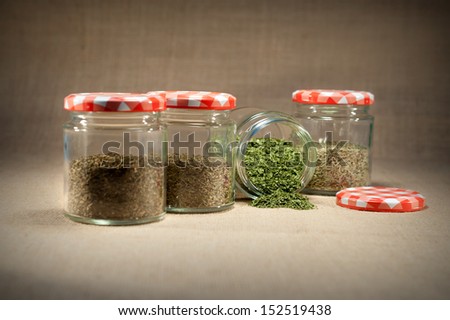 glass jars with herbs isolated on rustic background