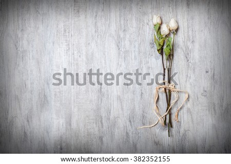dry white roses with ribbon on its stem on wooden table