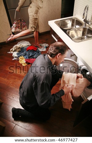 Man puts clothes into the washing machine while woman is going away