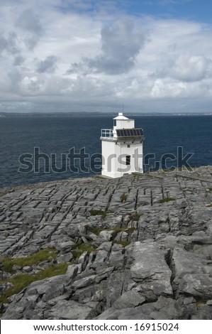 Cliffy coast of the Atlantic Ocean in The Burren, famous natural landmark of Ireland with the lighthouse Blackhead. County Clare, West Coast of Ireland