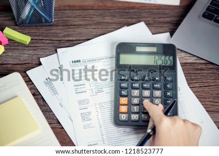 Woman hand using calculator Individual income tax return, taxation without representation, writing U.S. tax form 1040, time to payment concept.