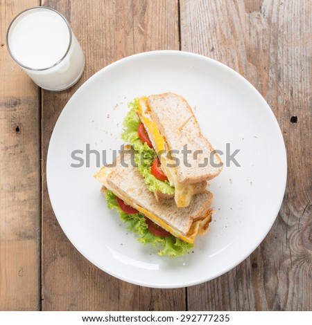 Sandwichs fried egg with cheese and milk on wood table.