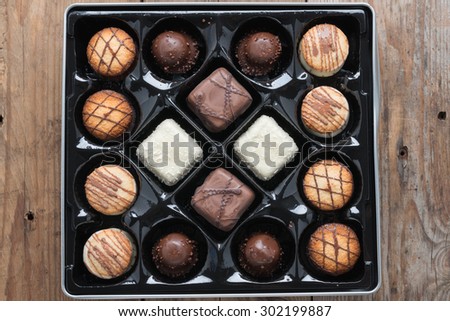 Box of assorted chocolates on wood background.