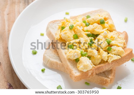 Scrambled eggs on toast, garnished with onion.