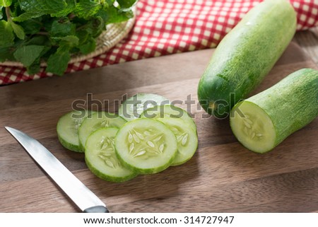 Fresh cucumber slices on wood cutting board.