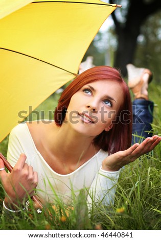 beautiful girl relaxing on grass under yellow umbrella