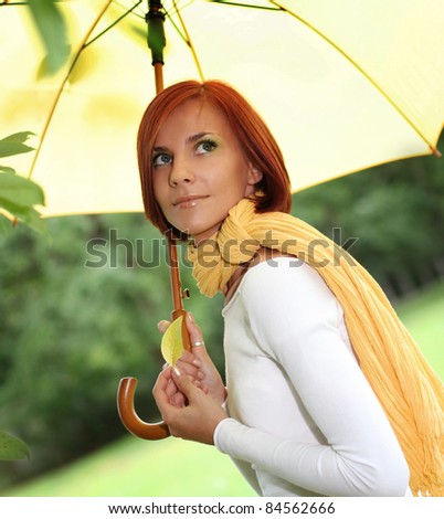 beautiful young girl under yellow umbrella in the autumn park