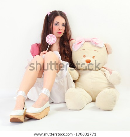 cute young woman dressed as a doll holding big bear