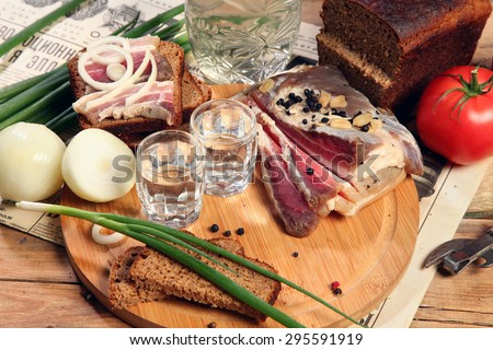 Vodka and smoked meat on wooden table