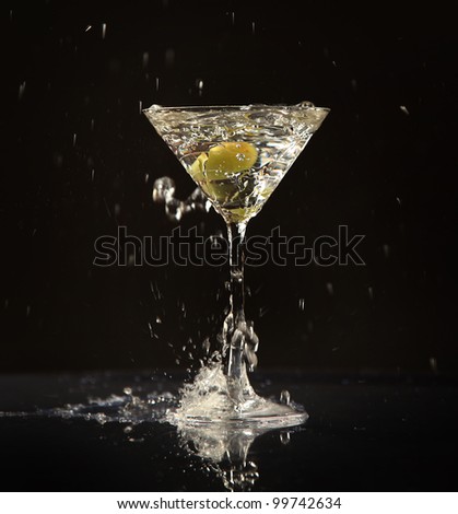 Olive splashing into martini cocktail