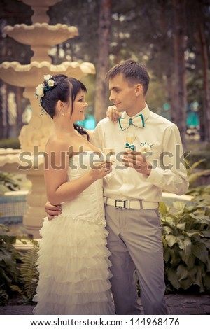 bride and groom drinking champagne on the background of the fountain