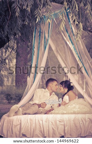 the groom and the bride on the bed in the park under a canopy. Funny just married.