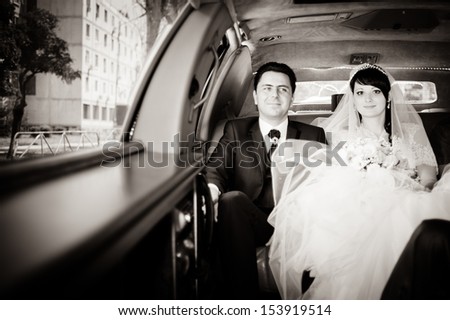 bride and groom in a wedding limousine with a bouquet