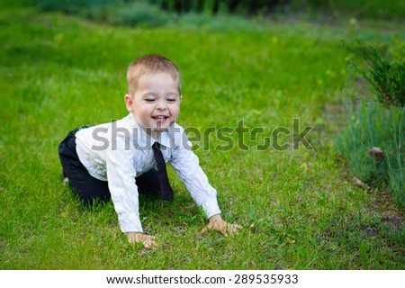 little boy in a shirt and trousers on a green lawn