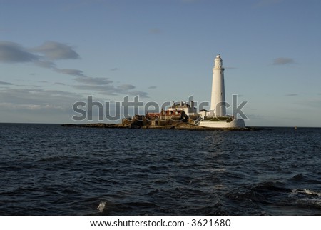 St Mary\'s Lighthouse at Sunset with the tide coming in covering the causeway to the island
