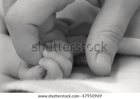 Baby\'s hand keeping adult finger