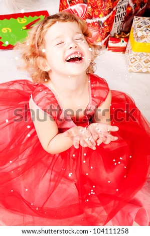 A girl under the Christmas tree with gifts, the girl is happy snowfall and catches it with his hands