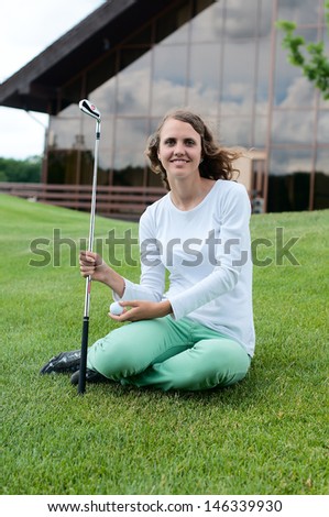 Girl golf player teeing off with driver from tee box, front view.