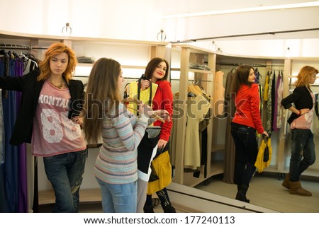 Woman shopping choosing dresses looking in mirror uncertain. Beautiful young multicultural shopper in clothing store.