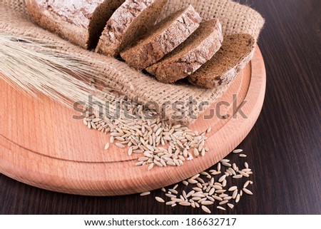 Dark bread on the wooden board, spikelets of wheat grain