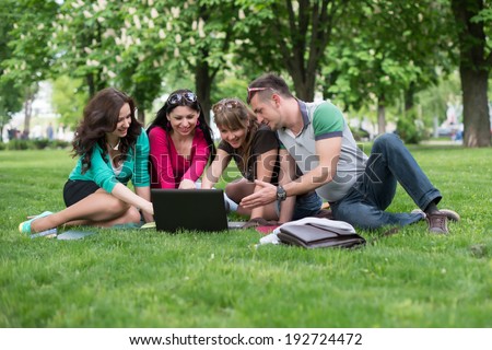 Group of young student using laptop together in the park