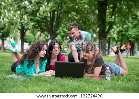 Group of young student using laptop together in the park