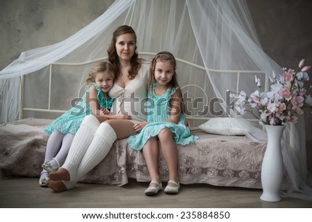 Over head view of a young pregnant mother and her young toddler daughter being playful in bed and having fun while at home, interior.