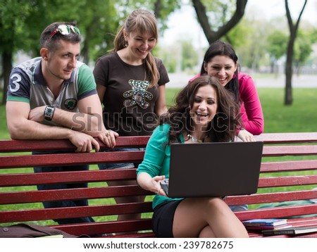 Group of young college students using laptop in the park