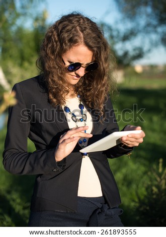 closeup of happy woman in glasses using tablet pc in the park