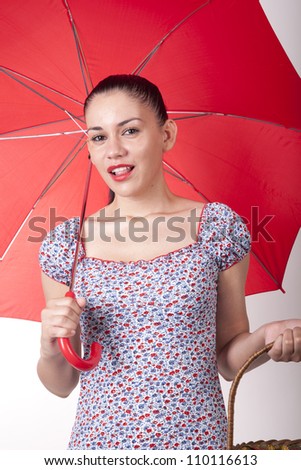 Portrait of a young attractive woman with red umbrella and basket.