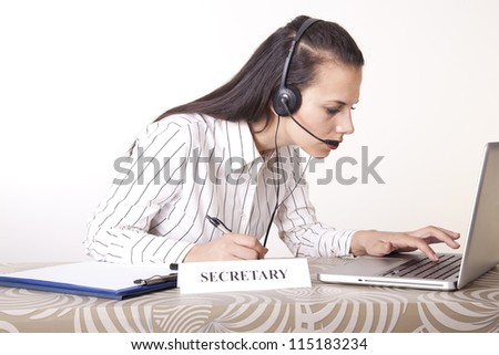 Portrait of a young beautiful secretary with headphones working.