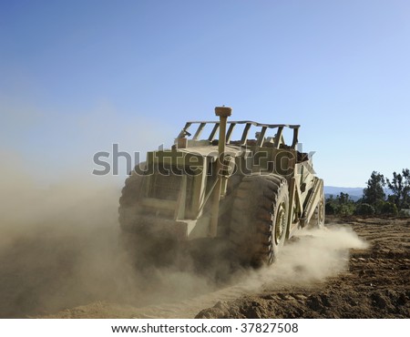 Heavy machinery earth mover, leaving trail of dust.
