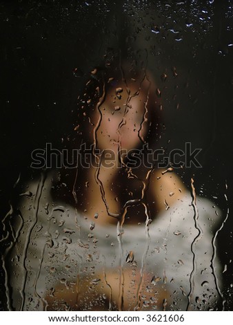 girl sitting behind the rainy window