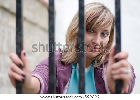 cute girl is looking through the bars