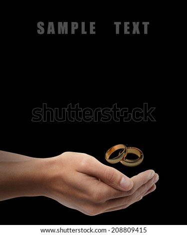 Man hand holding object ( Gold Wedding Rings ) isolated on black background. High resolution