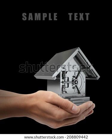 Man hand holding object ( Bank Safe in form houses ) isolated on black background. High resolution