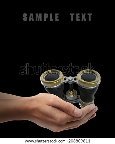 Vintage binoculars. Man hand holding object isolated on black background. High resolution