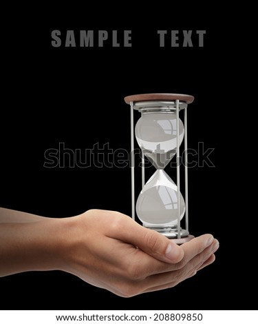 hourglass sand clock. Man hand holding object isolated on black background. High resolution