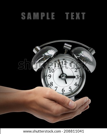 Old-fashioned alarm clock. Man hand holding object  isolated on black background. High resolution