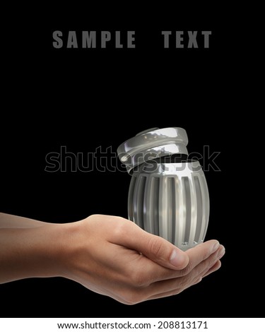 Steel trash can. Man hand holding object  isolated on black background. High resolution