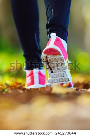 Woman jogging away from camera wearing trainers