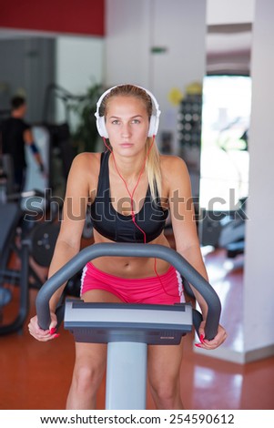 young fit woman doing sport spinning with headset in the gym