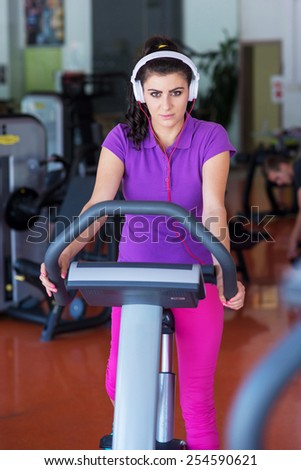 young woman doing sport spinning with headset in the gym