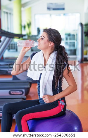 Fitness young woman relax with water bottle on exercase ball in the gym