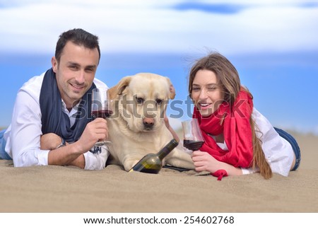 beautiful young happy couple enjoying at sea with their dog