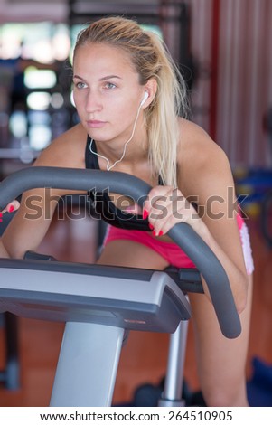 beatiful young woman doing sport spinning with headset in the gym