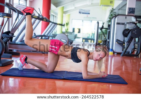 Beautiful young fit woman doing exercises on the floor at the gym