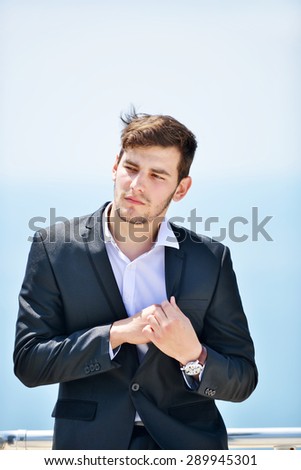 Businessman standing at the balcony near sea under blue sky